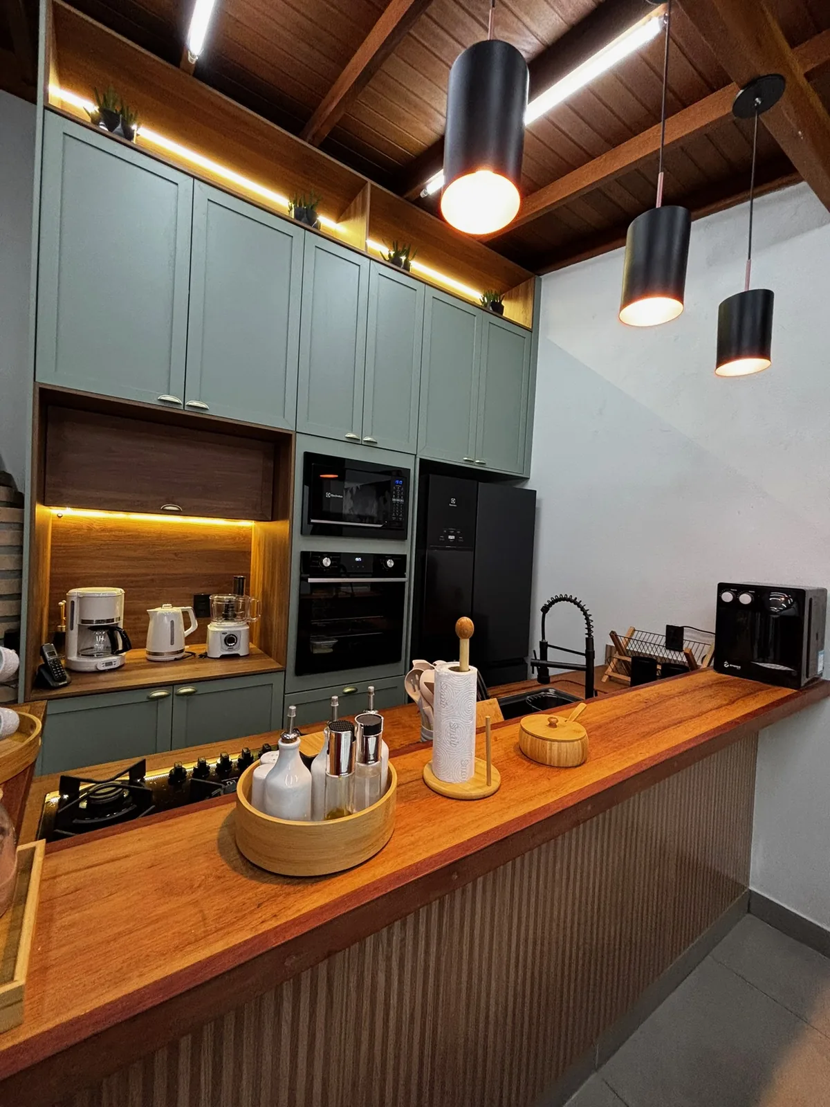 Área gourmet com armários planejados, revestimento claro e bancada de apoio.